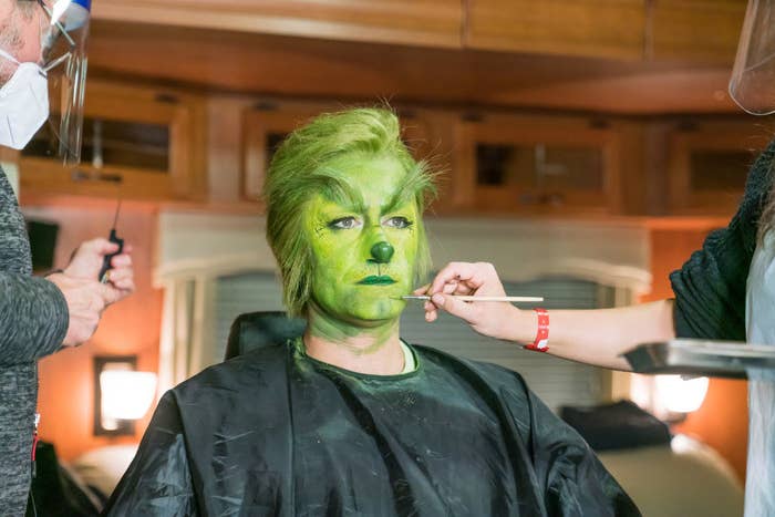 Matthew Morrison sitting in the makeup chair getting his grinch makeup applied. 