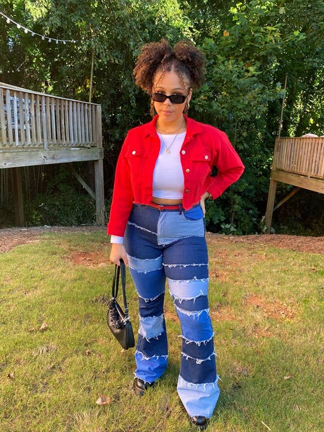 reviewer wearing the flare jeans with patches of different colored blue denim