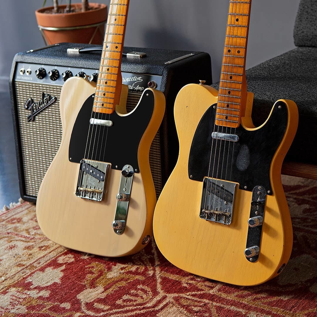 A pair of Fender guitars resting on against a Fender speaker on a rug
