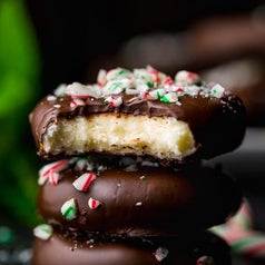 A stack of chocolate-covered peppermint patties with crushed candy canes on top.