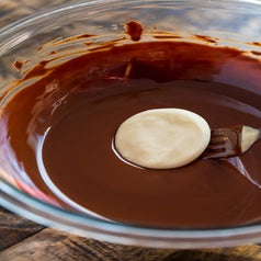 Dipping a peppermint disk into melted chocolate.