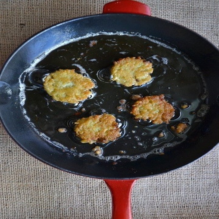 Tater tot latkes frying in a skillet.
