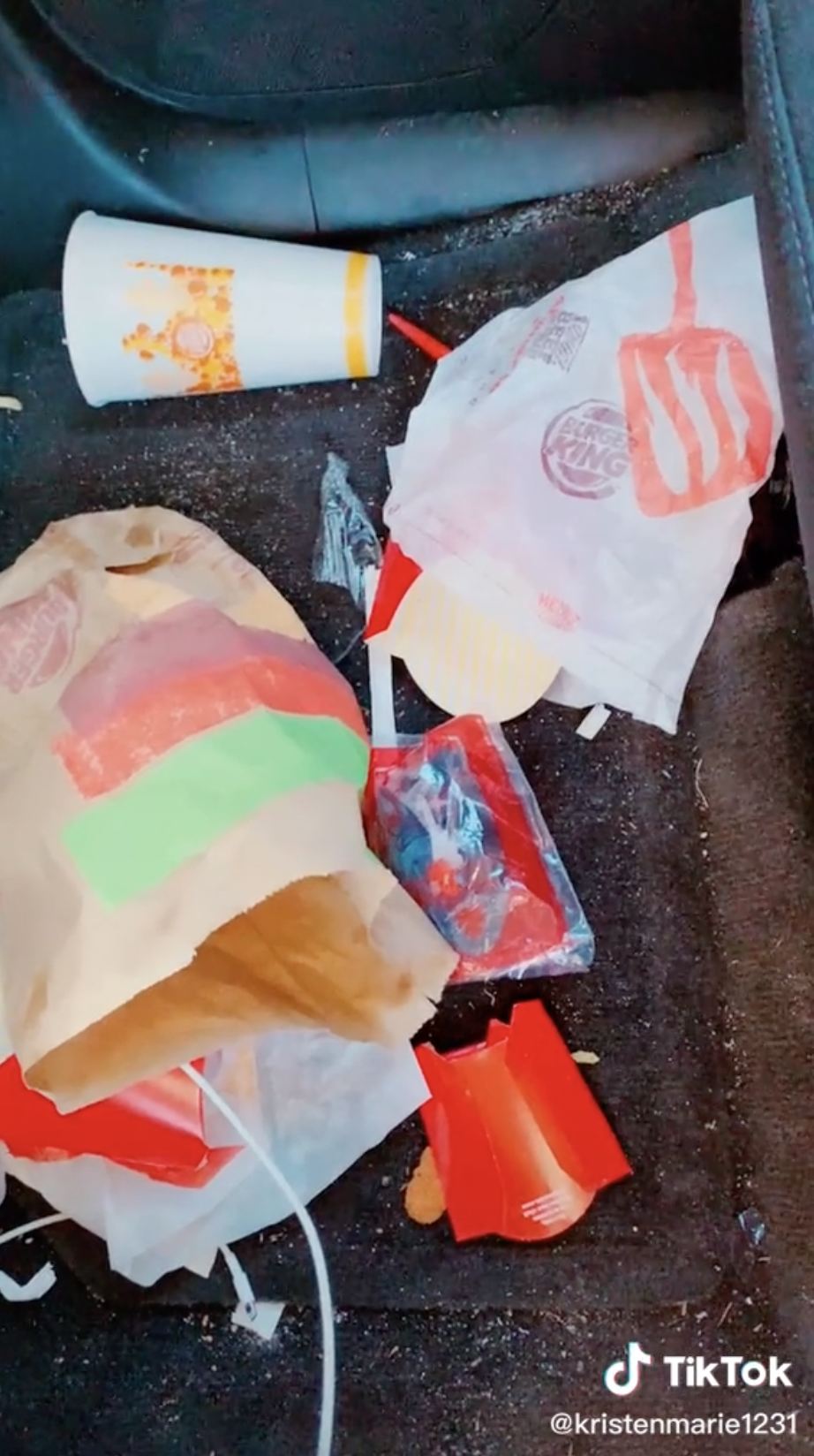 Photo of a happy meal and trash inside back seat of car.