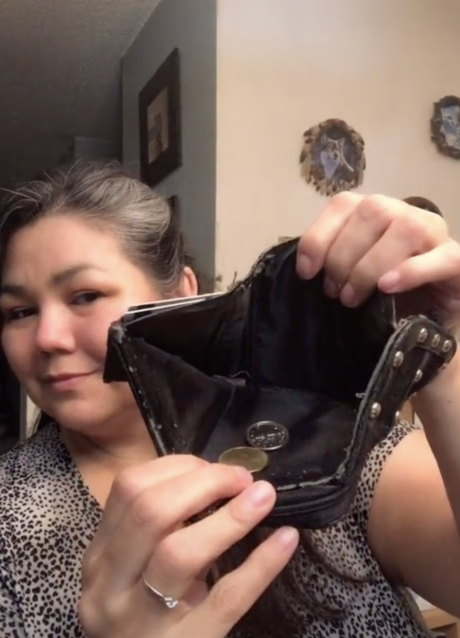 Woman holding up a wallet with just a bit of change.