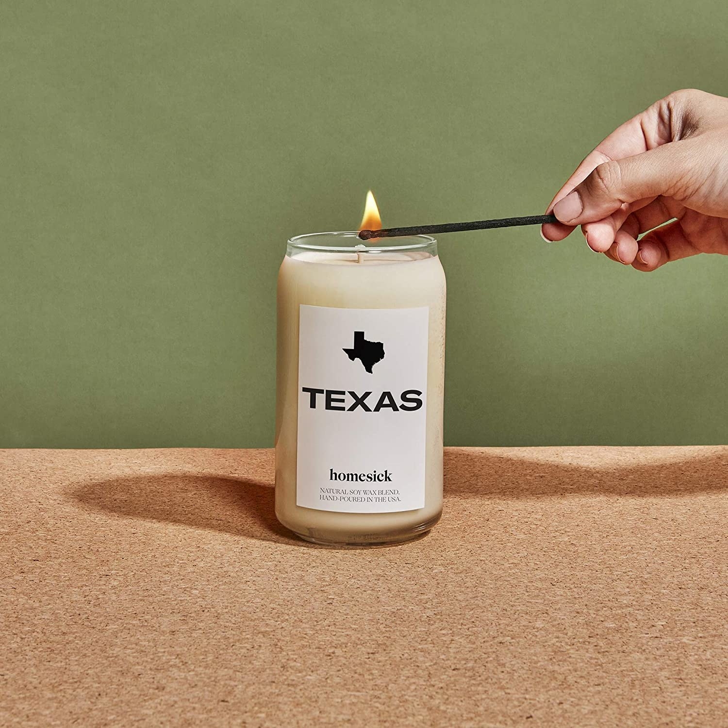 Model lights the Texas candle in front of a green wall