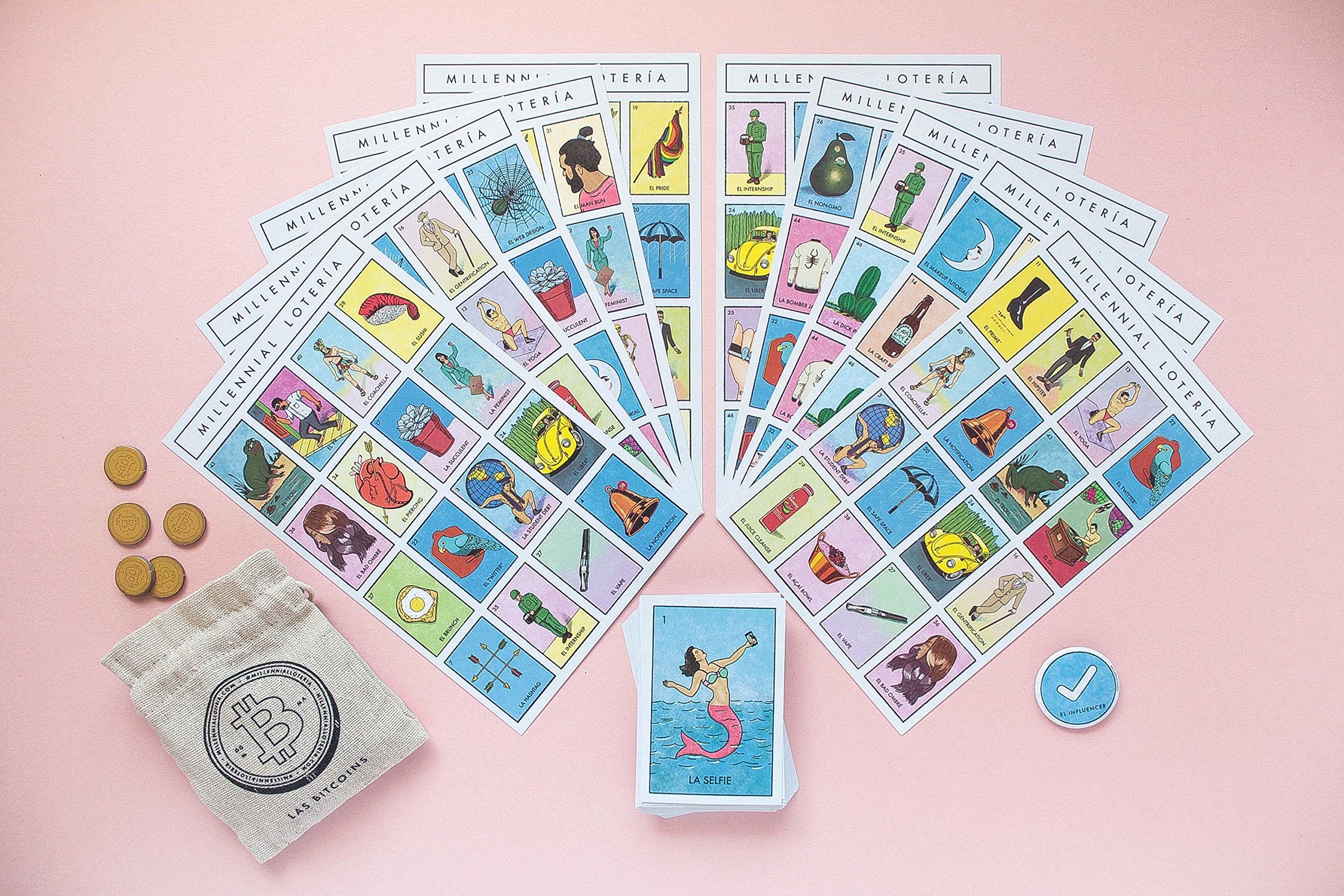 the Millennial Loteria game cards spread out on a pink table top