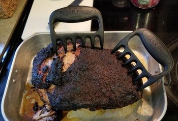 The review photo of the Bear Paws Shredder Claws sticking out of a full roast pork