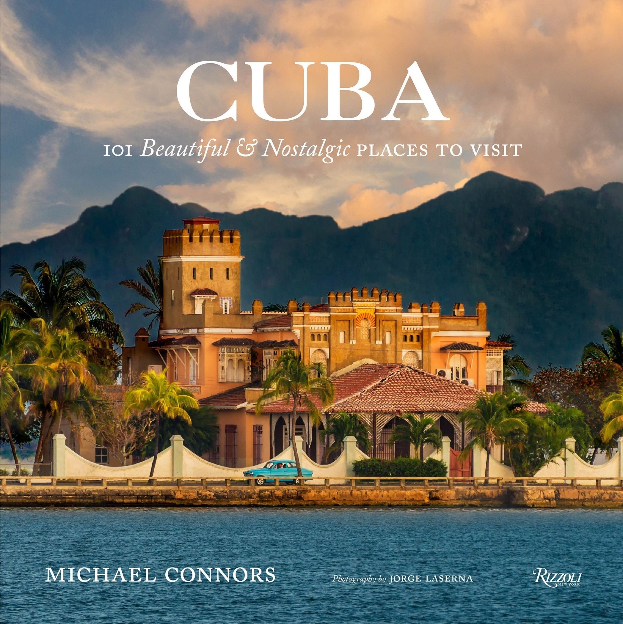 the book cover featuring a seaside mansion with a blue 1950s car driving in front of it
