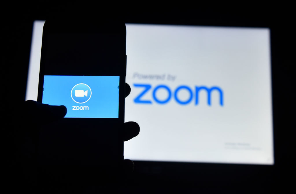 Photo of a hand loading the Zoom app logo onto their smart phone