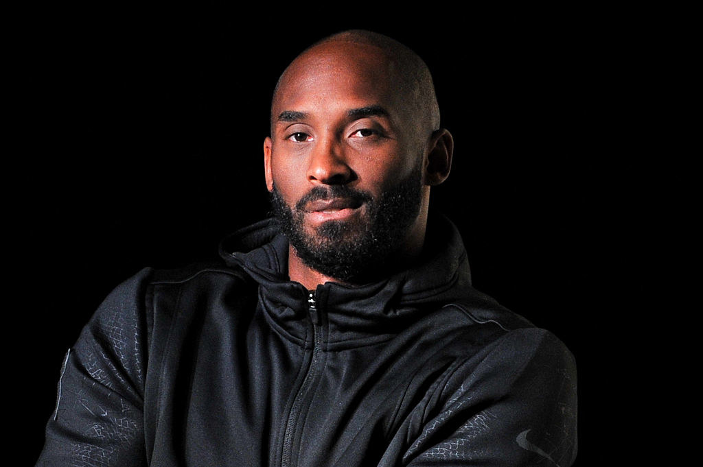 Kobe Bryant looking at the camera in a black working out jacket in front of black ground