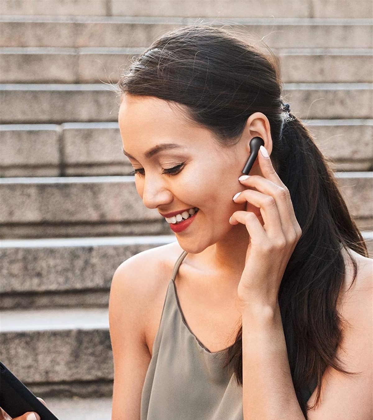 Model touching wireless earbud in left ear