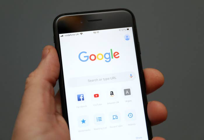 A person holds an iPhone with Google open