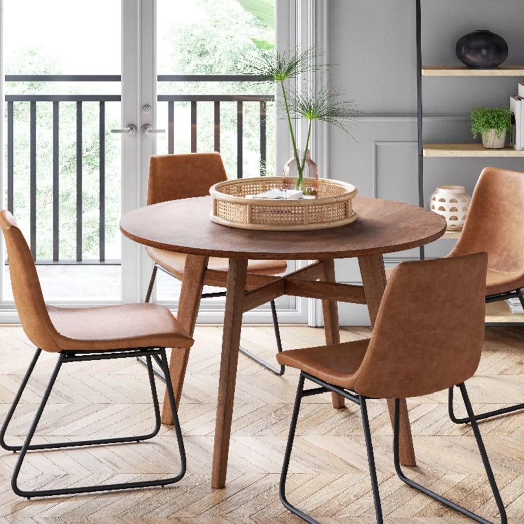 Four brown faux leather dining chairs with metal legs