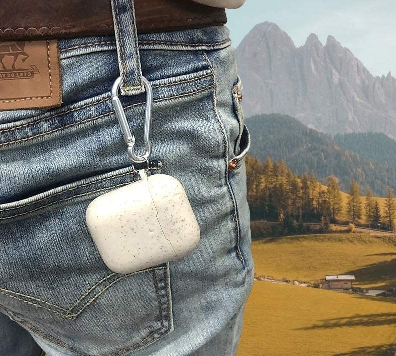 A person with their AirPods case on a carabiner attached to the belt loop on their jeans