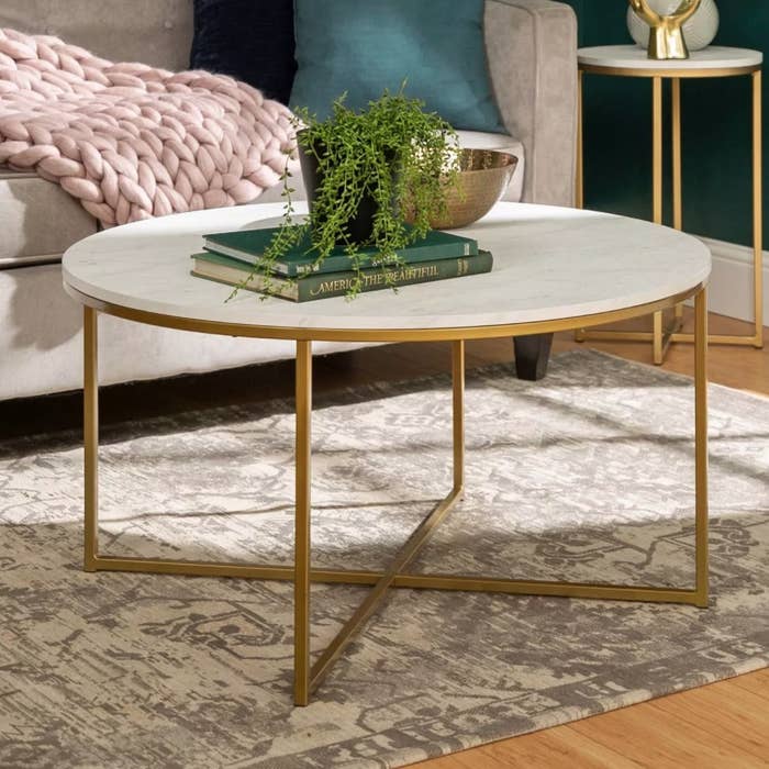 A round coffee table with metallic legs and white faux marble top