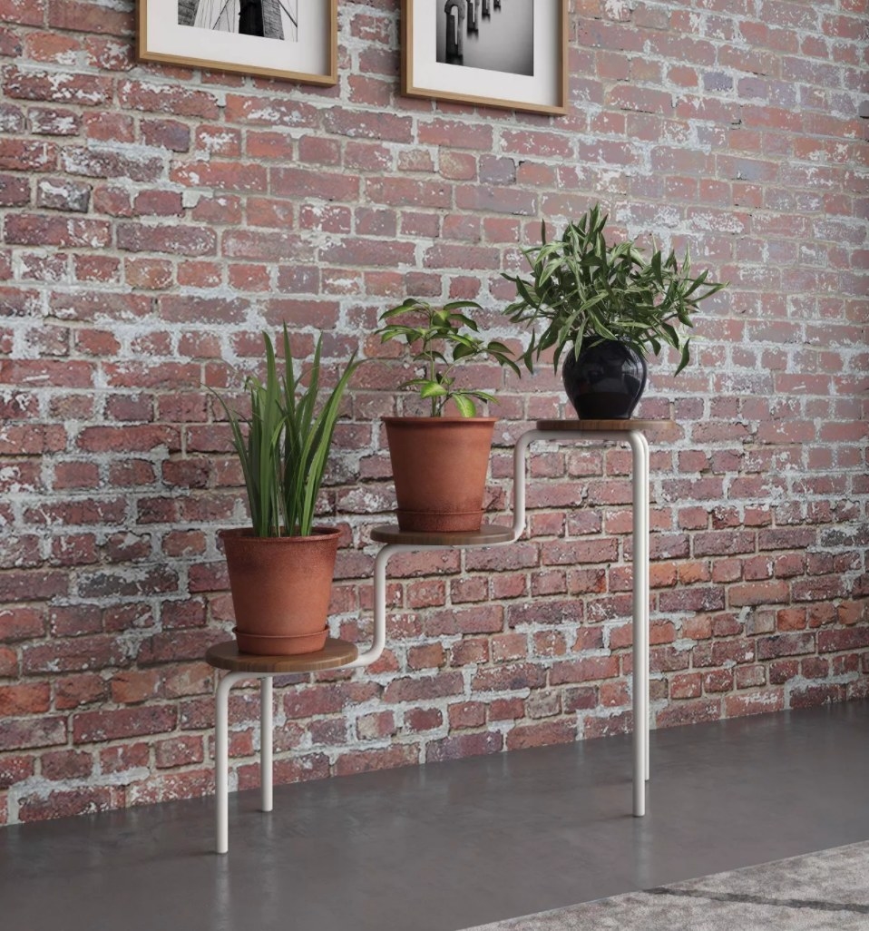 A three tiered plant stand with round wooden shelves and metal legs