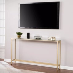 A skinny metallic console table with mirrored top