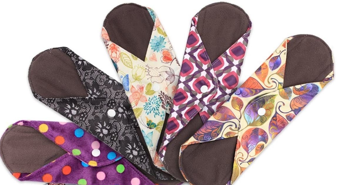 Bright patterned reusable menstrual pads with button clasps on their wings