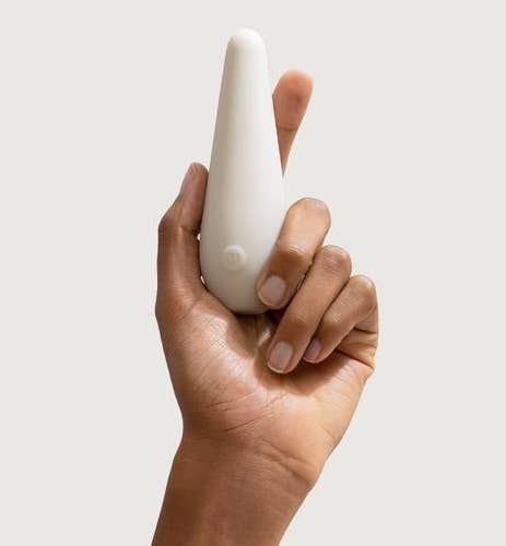 A hand holding a slim, white vibrator with a single button 