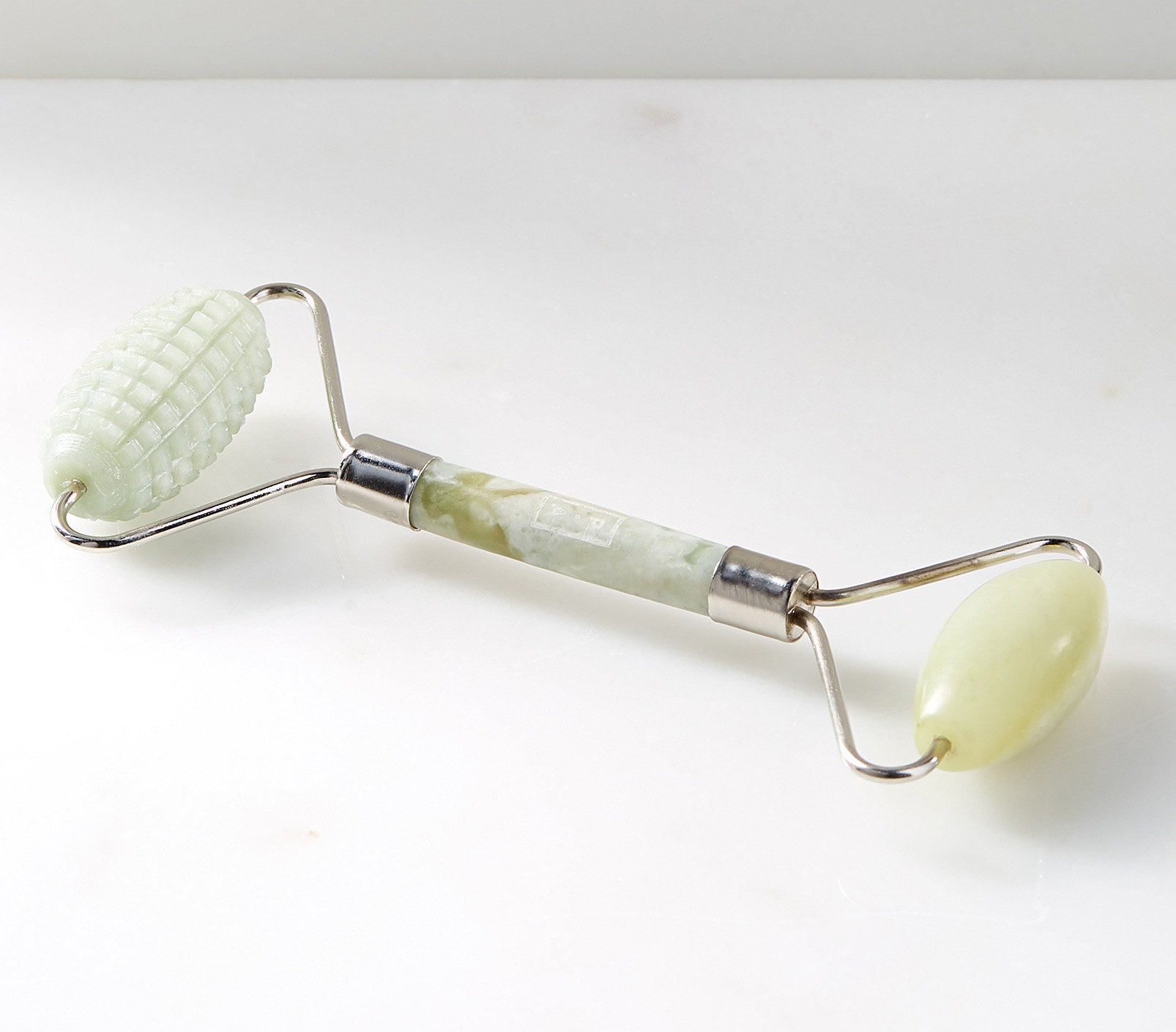A double-sided jade roller, with one smooth side and one rigid side for massaging 