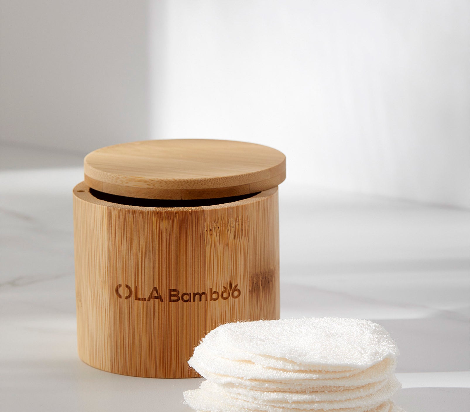 A stack of reusable beauty pads next to the cylinder bamboo container 