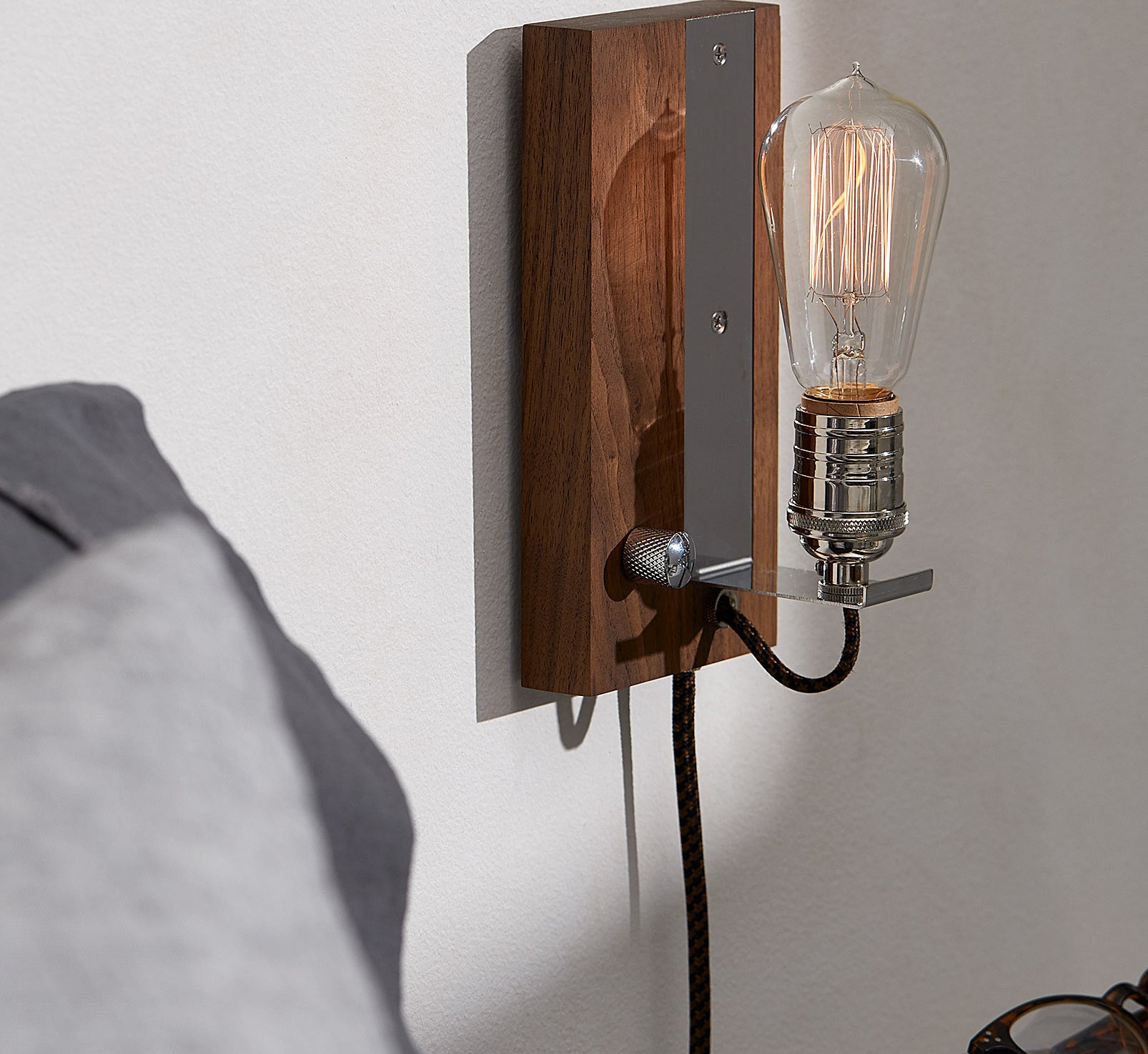 The vintage sconce mounted on a wall with the Edison bulb dimmed down 