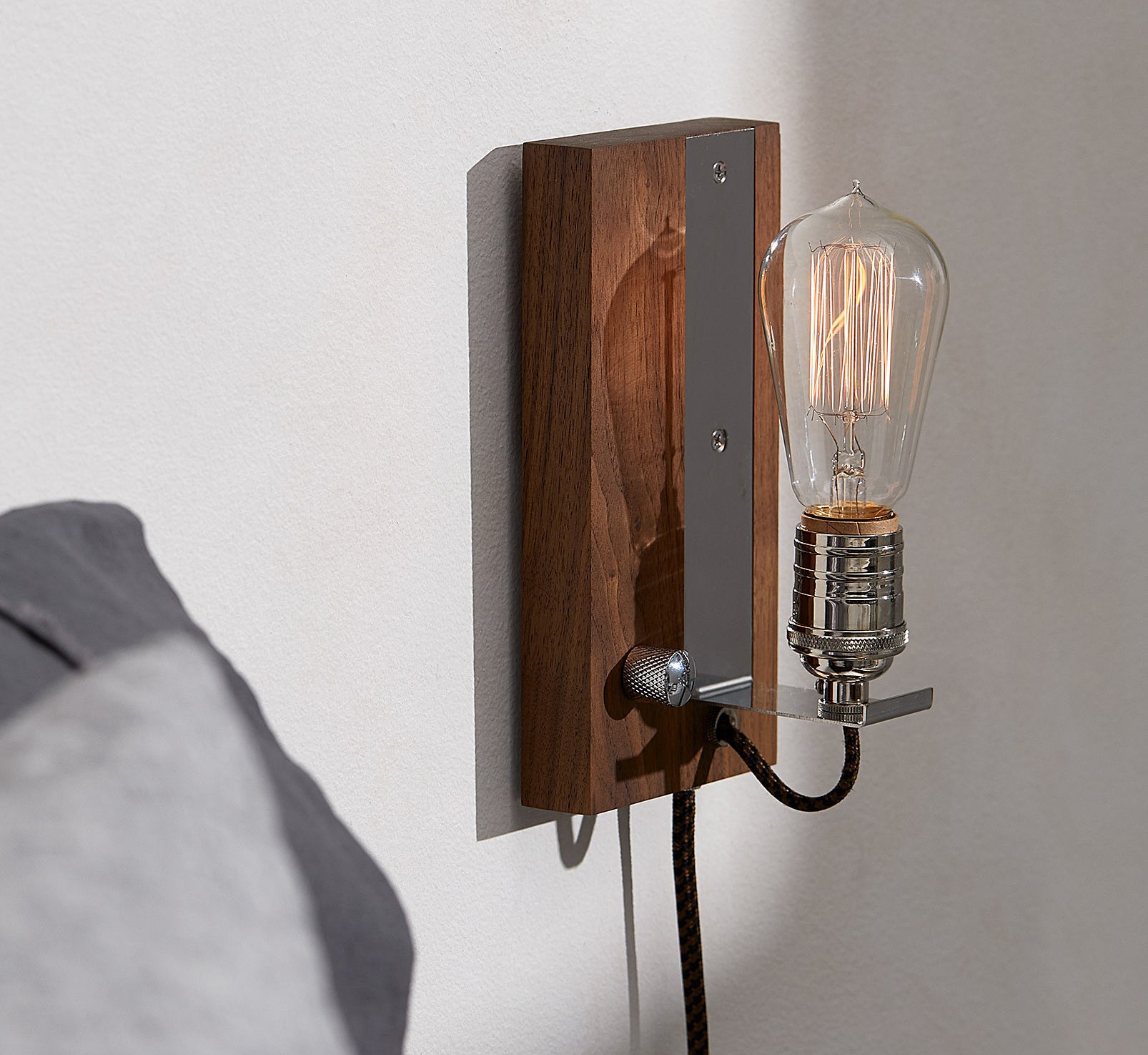 The vintage sconce mounted on a wall with the Edison bulb dimmed down 