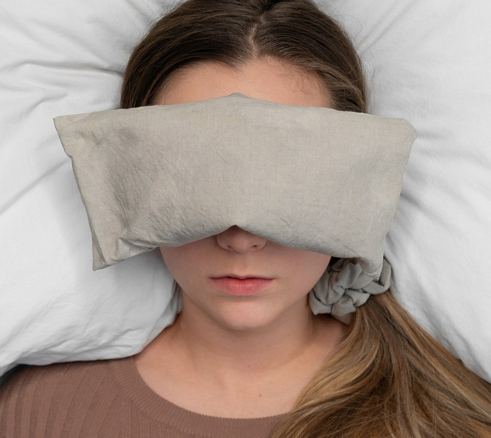 A person lying down with the eye cushion over their eyes