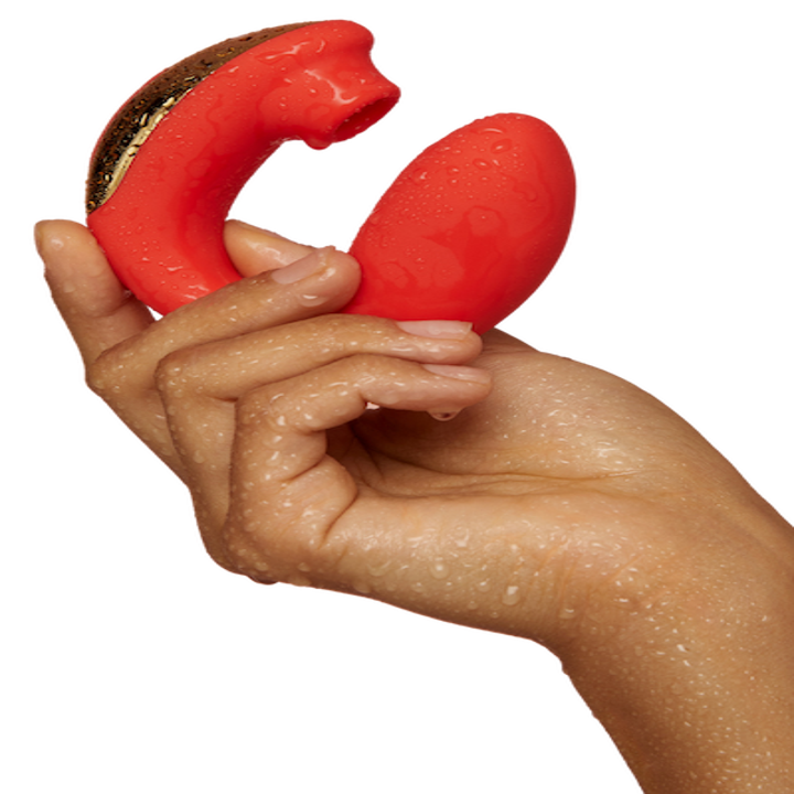 A hand holding the rabbit vibrator with an egg-shape on one end and a suction cap on the other 