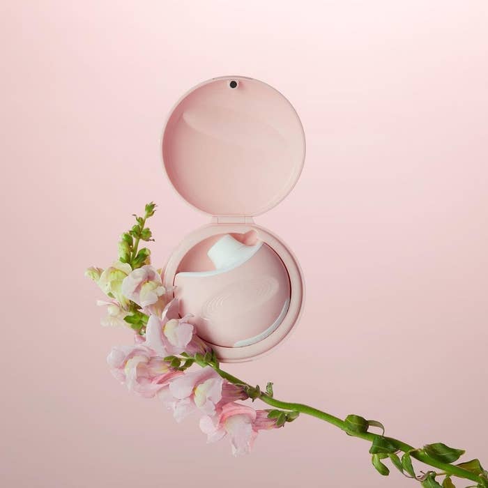 The round pink air vibe with a suction portion in its matching pink carrying case