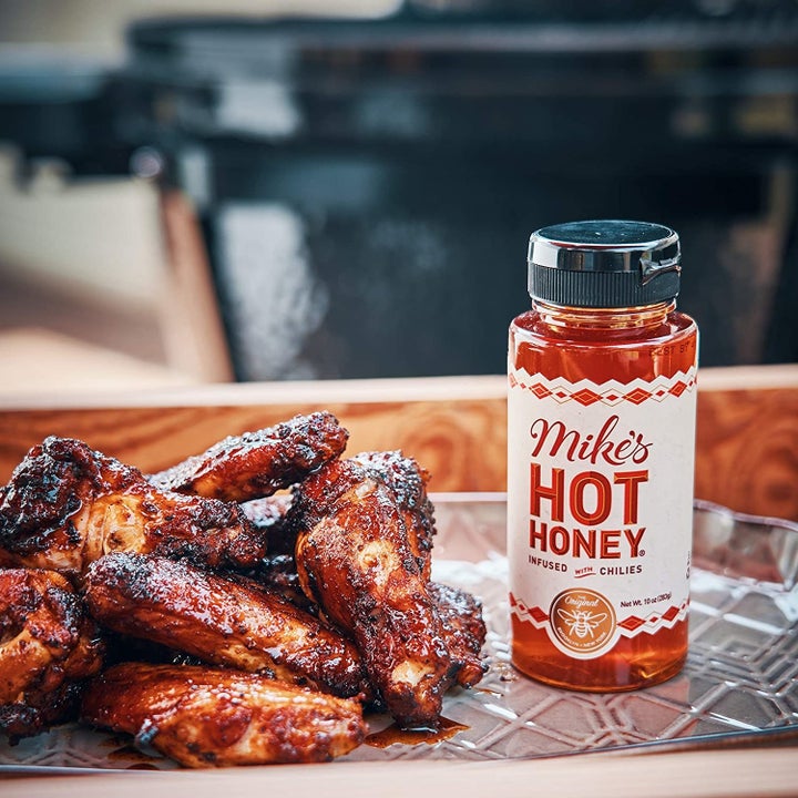 the bottle of the hot honey next to a pile of wings