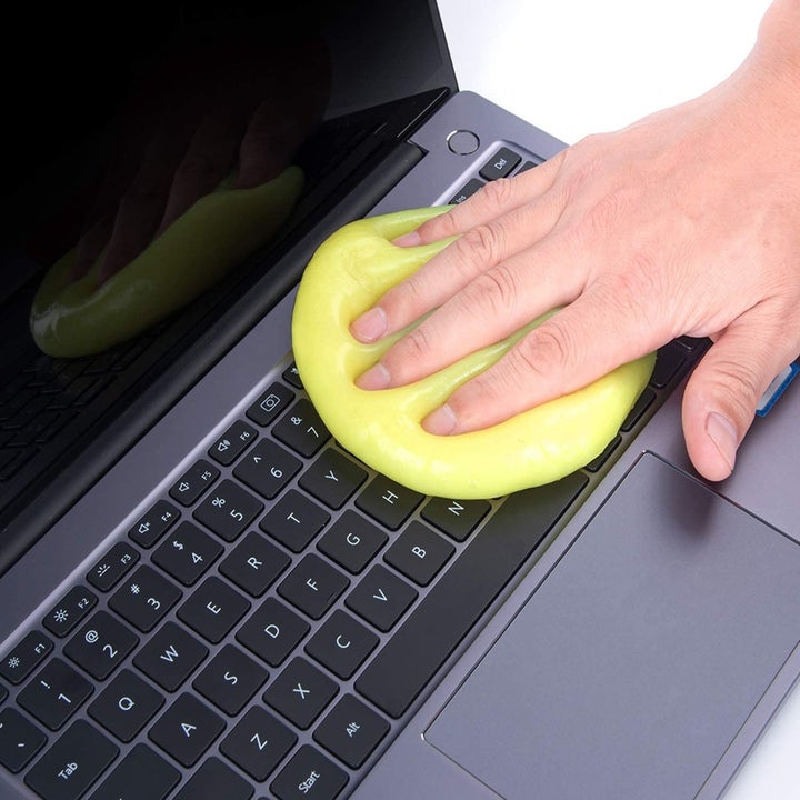 a person using the cleaning gel to clean their laptop keyboard 