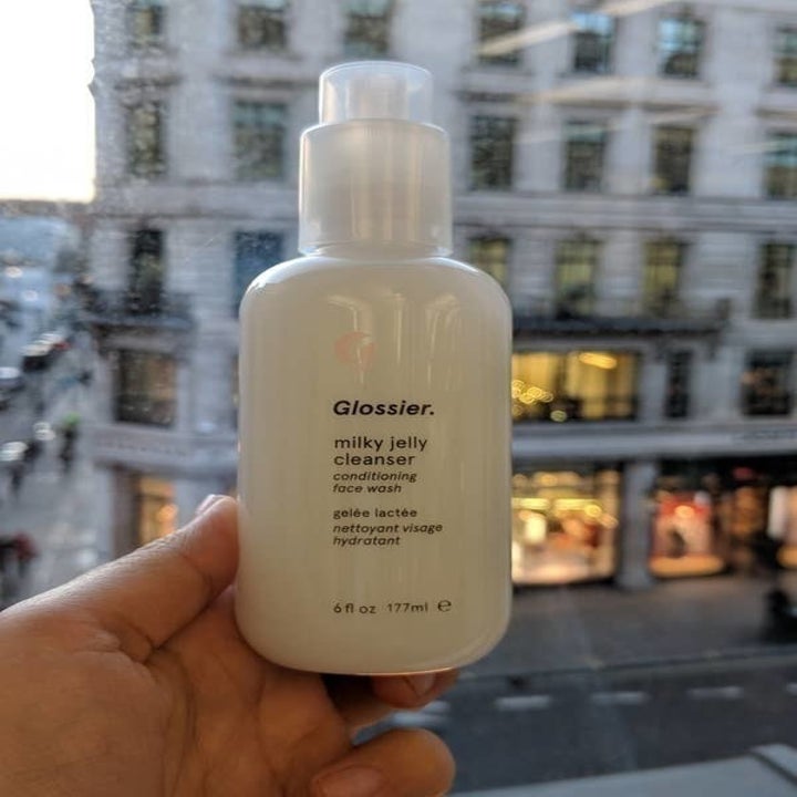 BuzzFeed Editor Ayesha Mittal holding the bottle of glossier milky jelly cleanser