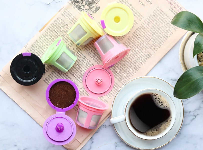 Reusable k-cups on a newspaper next to a cup of coffee 