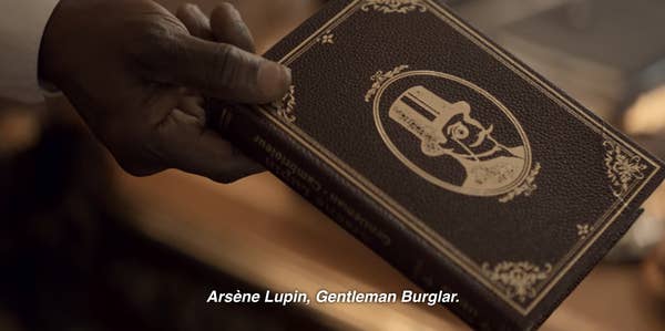 A scene from the show where Babakar hands Assane the Lupin book