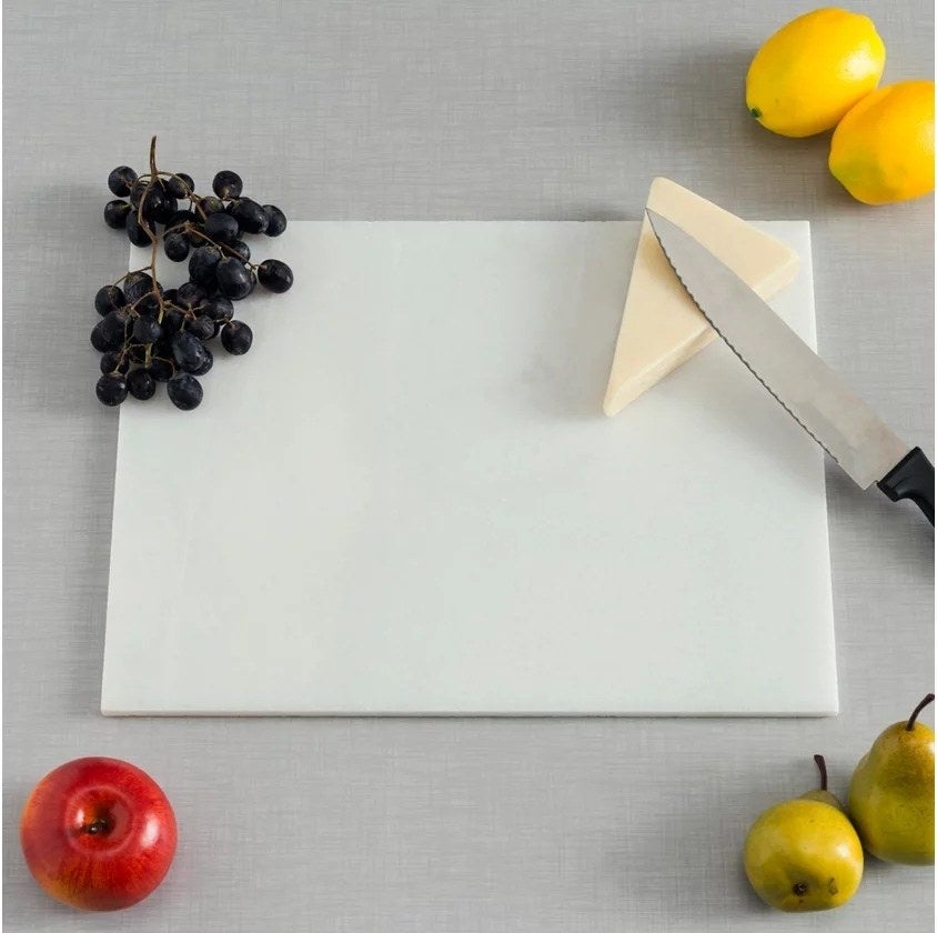 White Marble rectangular cutting board with a wedge of cheese and some grapes