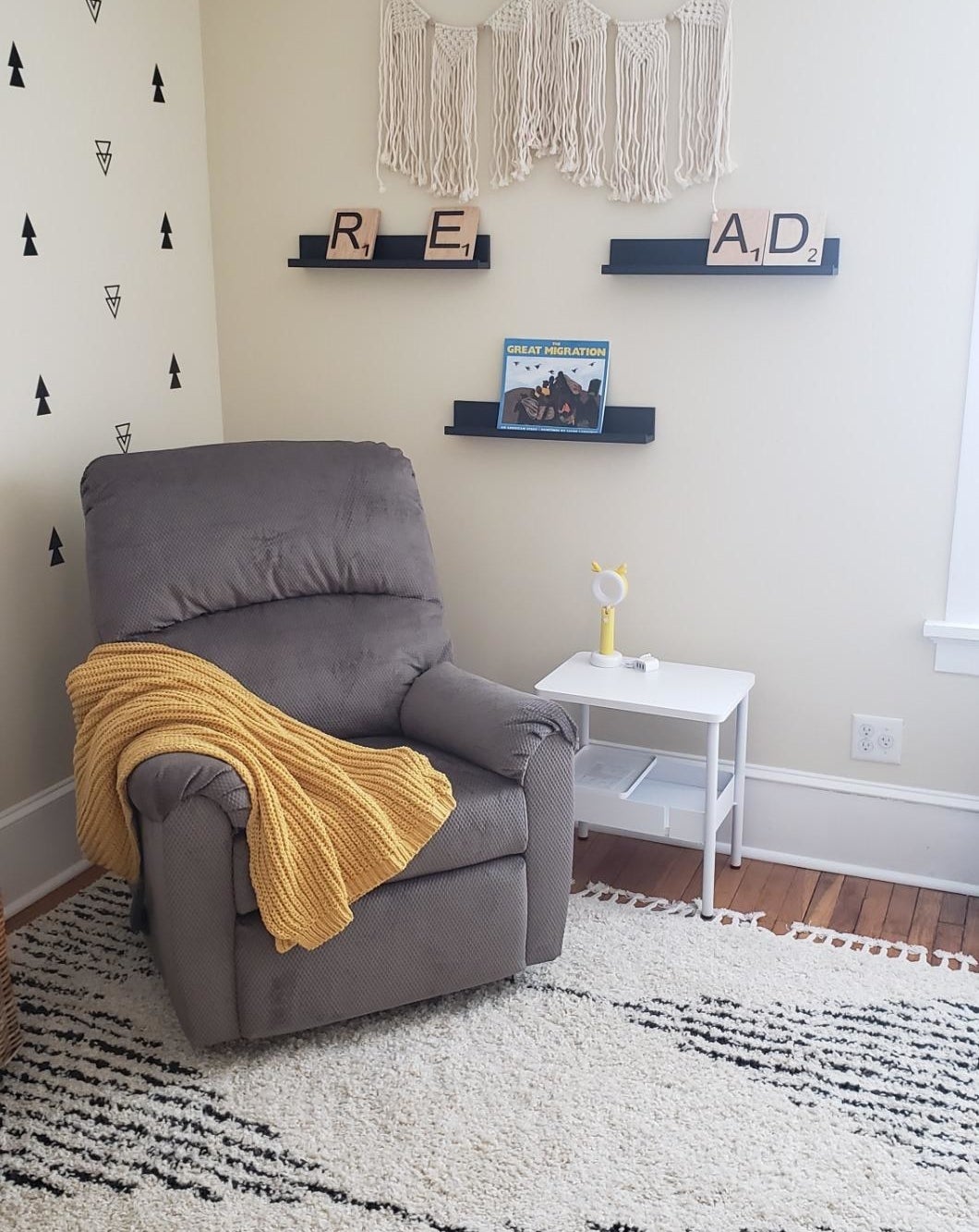 Reviewer&#x27;s nursery with a recliner and three black ledge shelves on the wall behind, displaying books