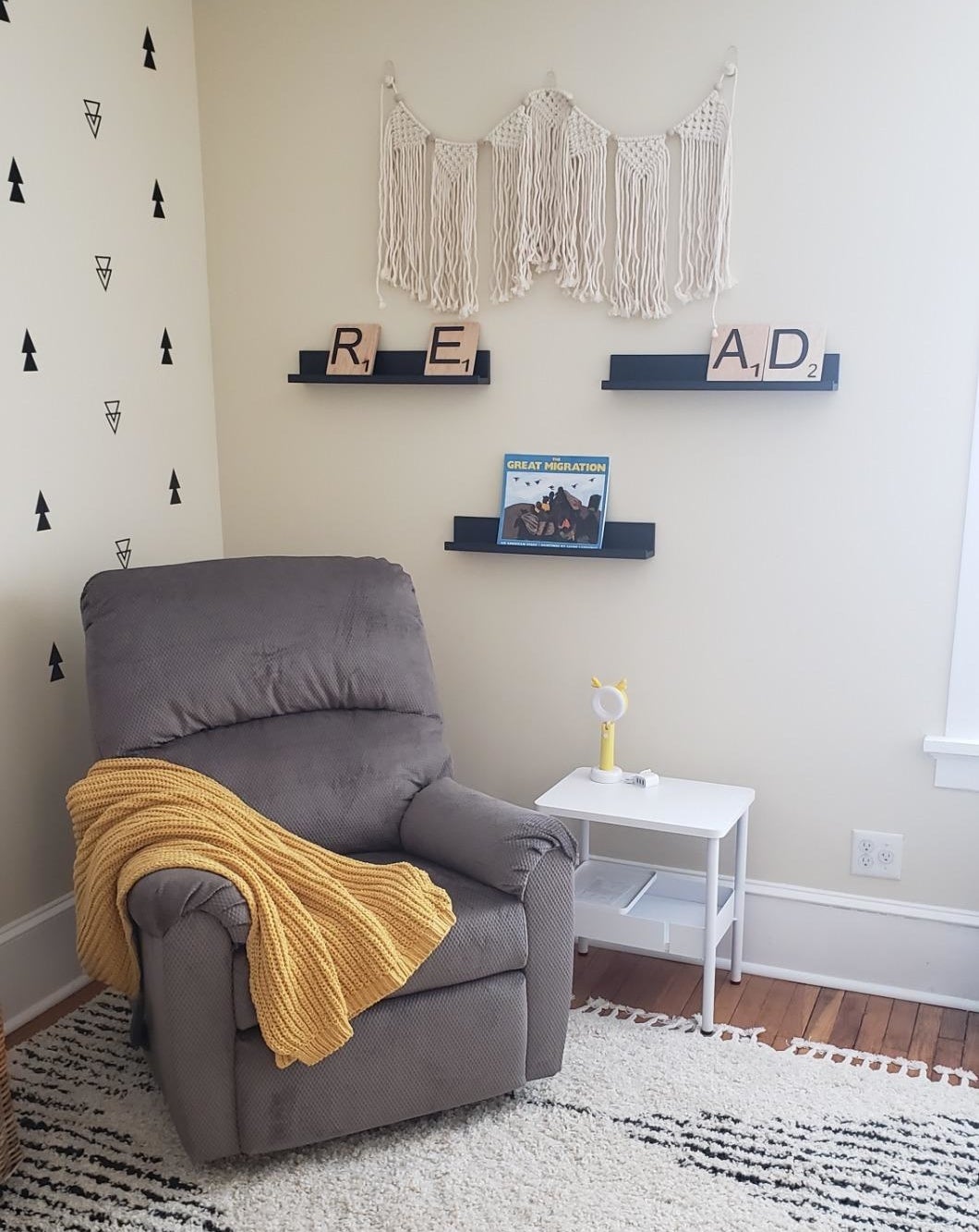 Reviewer&#x27;s nursery with a recliner and three black ledge shelves on the wall behind, displaying books