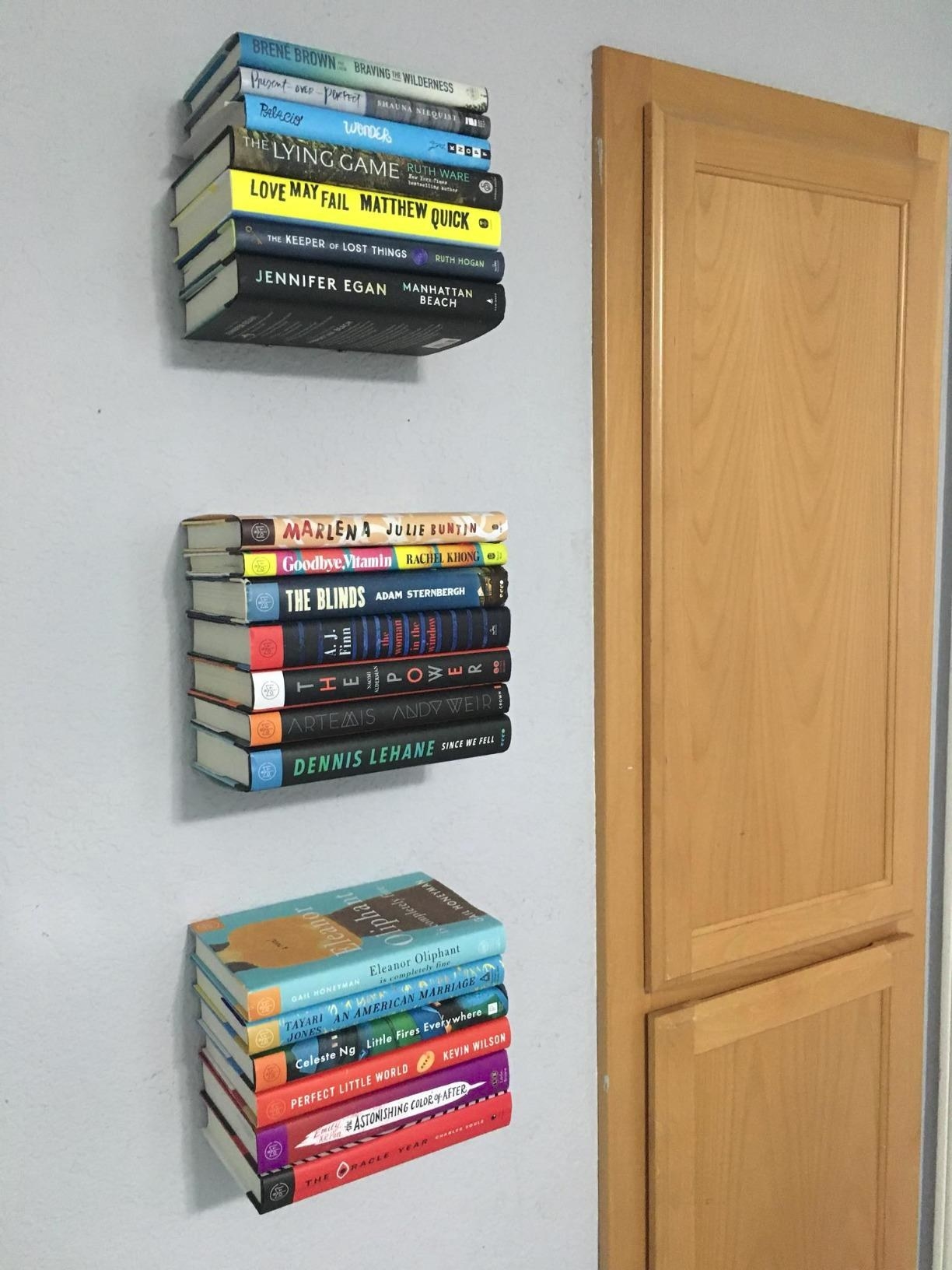 reviewer image of three of the shelves on the wall holding up three different stacks of books