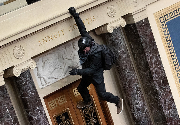 Rioter hangs from a balcony inside the Senate chamber