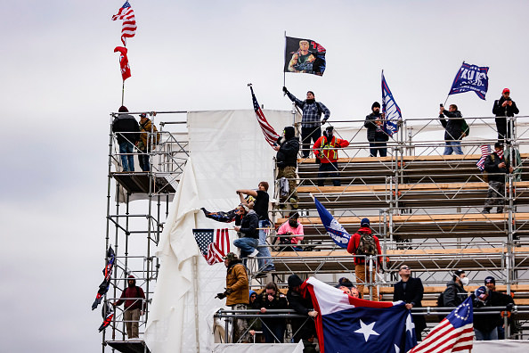 Pro-Trump supporters stand on scaffolding while waving flags