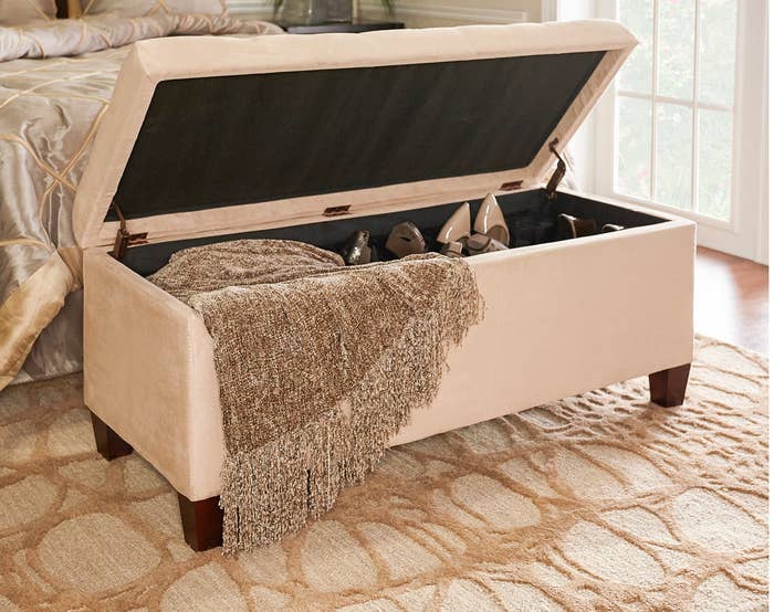 the storage ottoman with a blanket and shoes inside