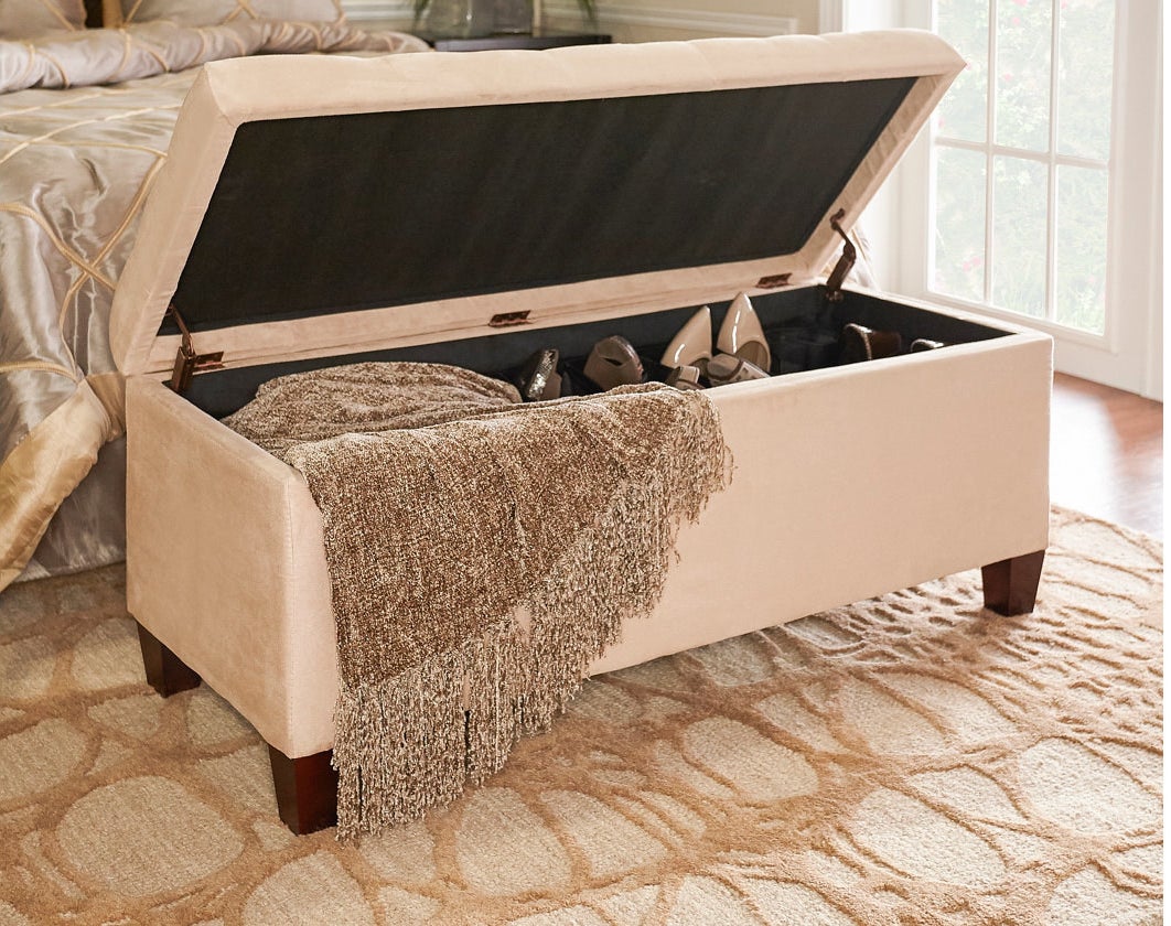 the storage ottoman with a blanket and shoes inside 