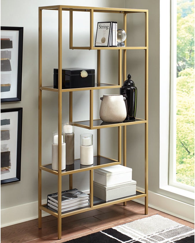 the golden bookcase holding candles and books 