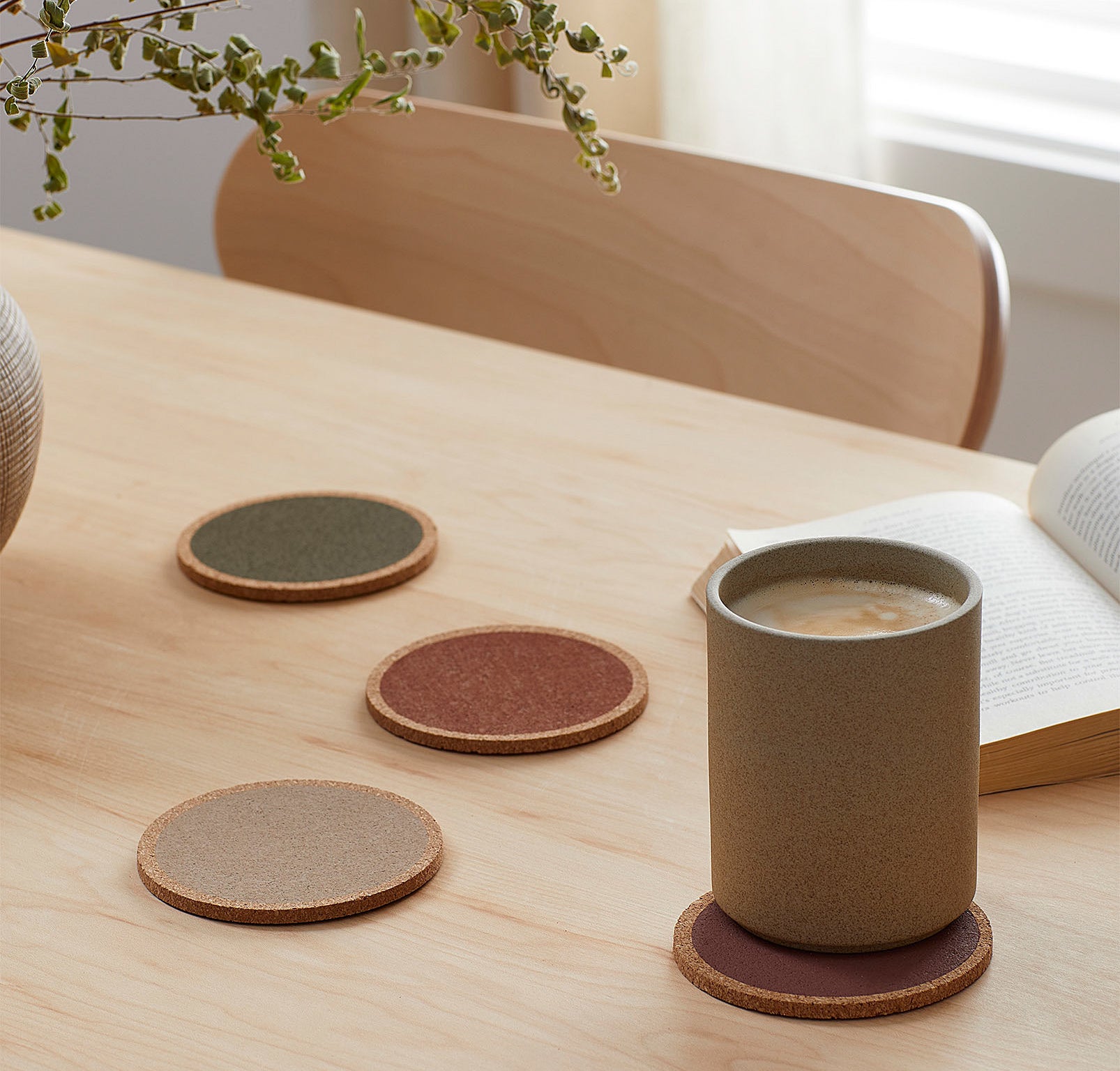 Four coasters on a table, one with a cute mug of coffee sitting on top