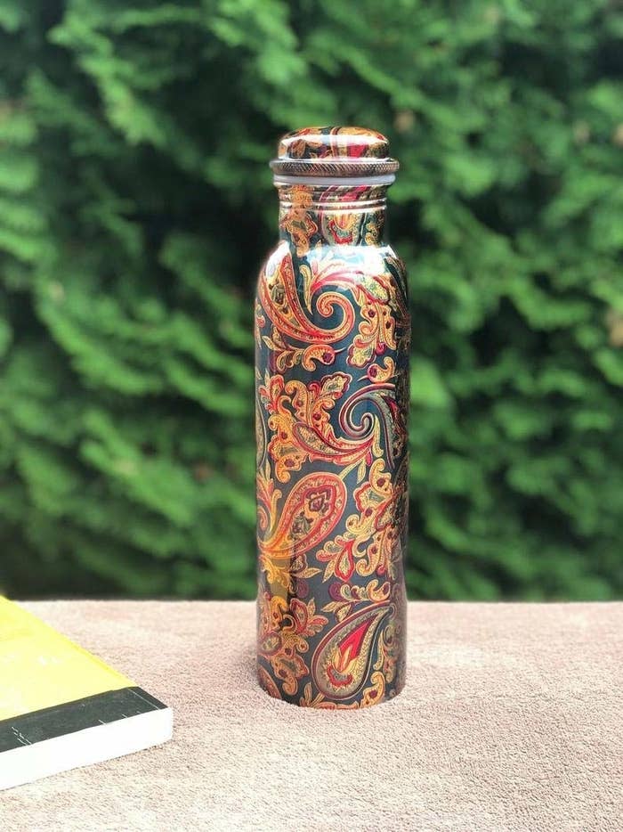 A copper water bottle with floral patterns