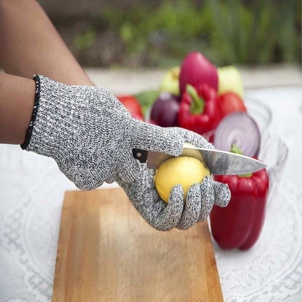 A person wearing the anti-cut gloves while cutting a lemon.