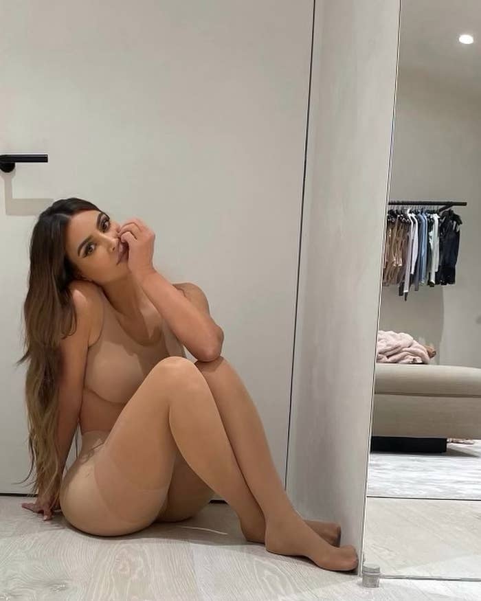 Kim poses in her shapewear as she sits on the floor with her hand held to her face