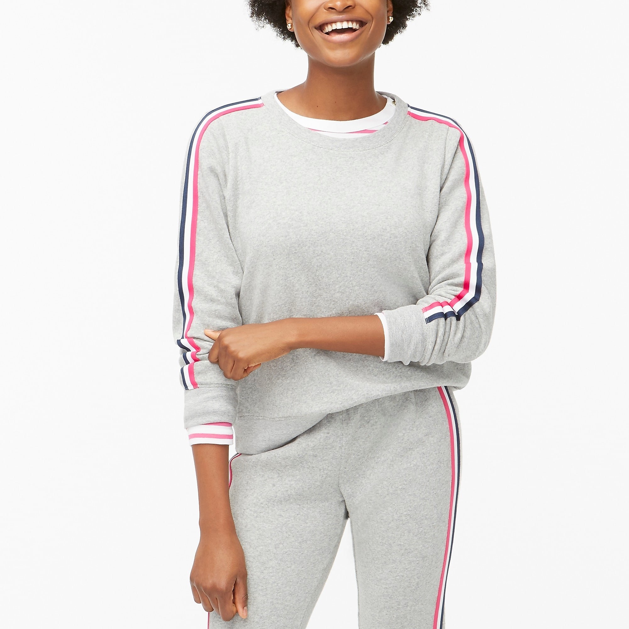 Model wearing the gray sweatshirt with pink, navy, and white stripes along sleeves