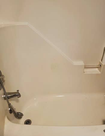 The same reviewer's shower wall no longer orange and looking clean after using the spray
